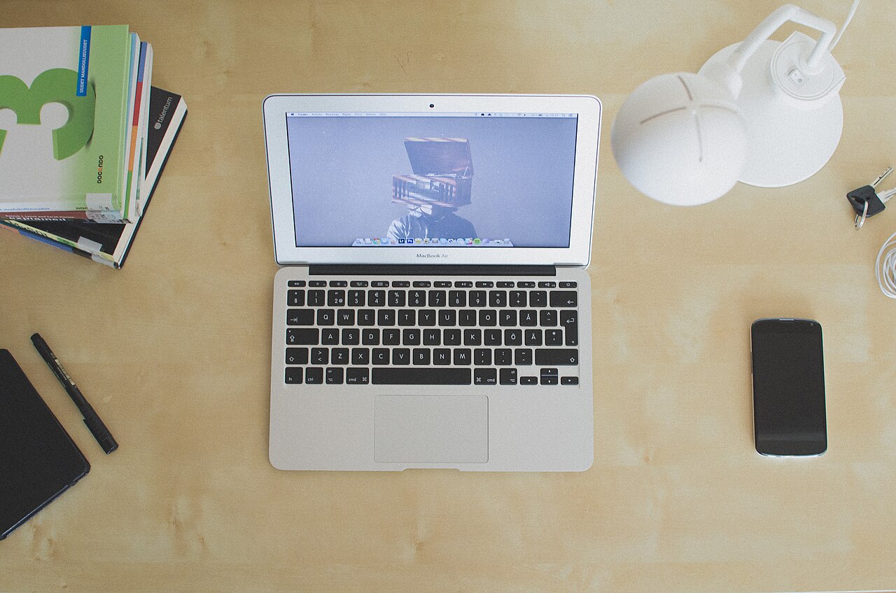 A laptop, phone and notebooks arranged on a desk